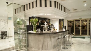 A modern bar area with a marble counter, glass display cases, and a seating area with stools. - Hotel El Faro Marbella (Marbella)