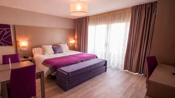 A hotel room with a bed, bedside tables, a desk, and a chair.