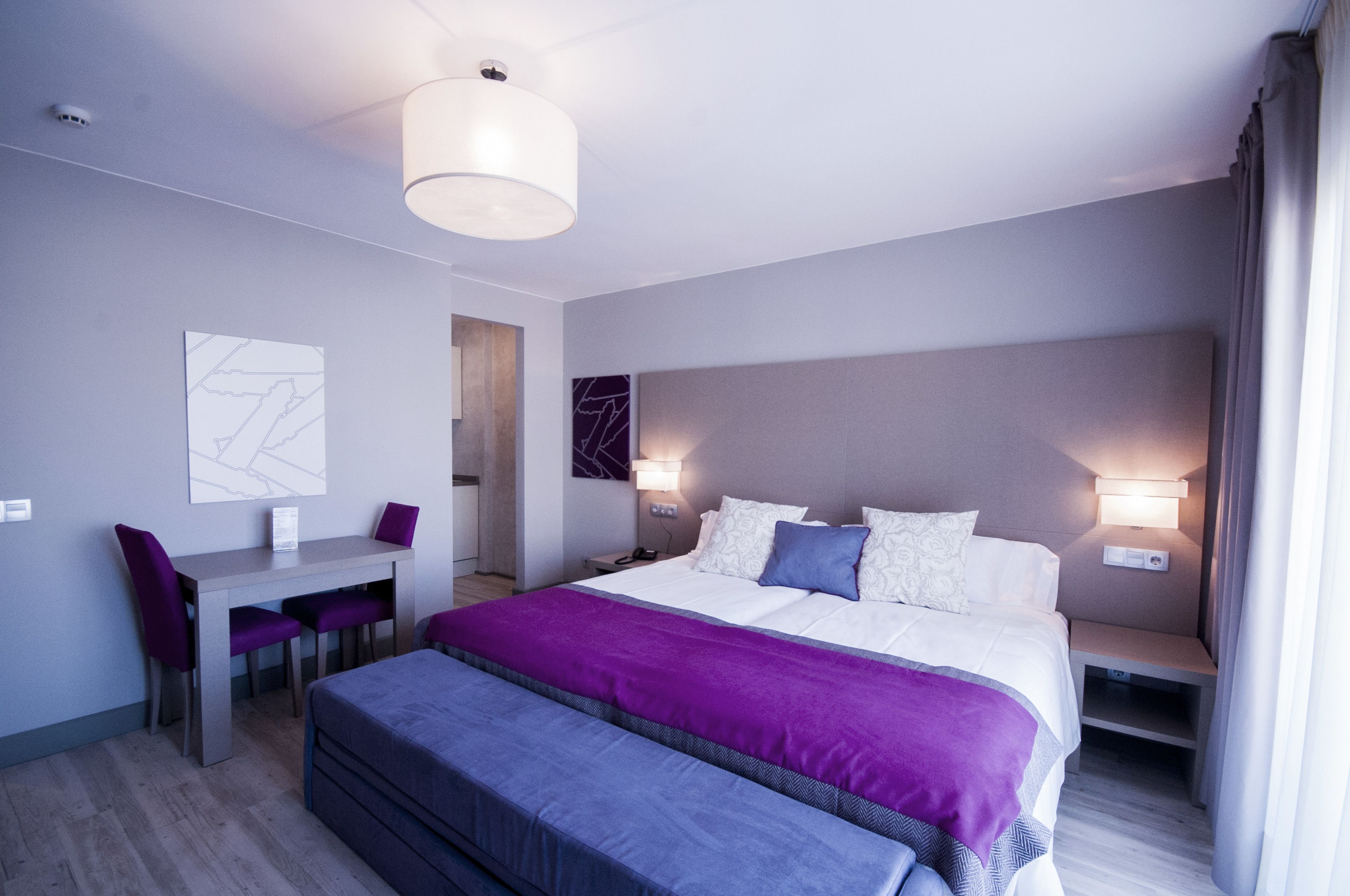 Una habitación de hotel moderna con una cama grande, un escritorio y una silla.