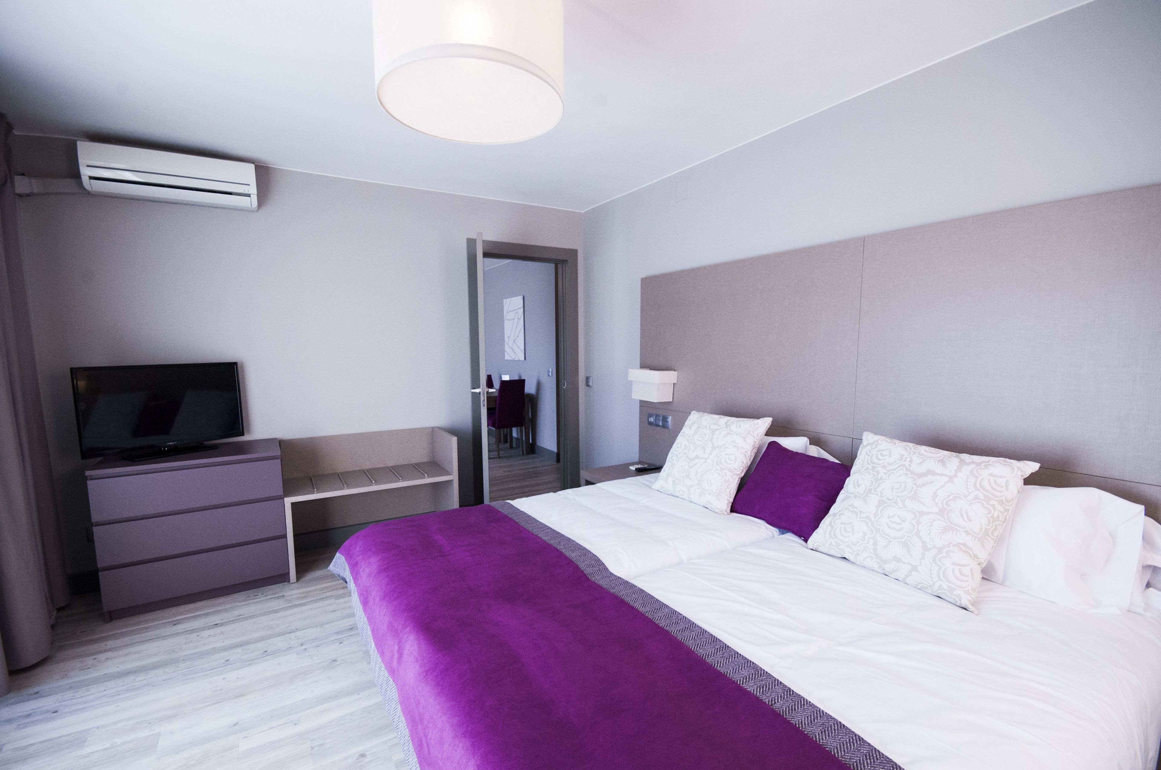 Una habitación de hotel moderna con una cama grande, un televisor de pantalla plana, un escritorio y un armario.