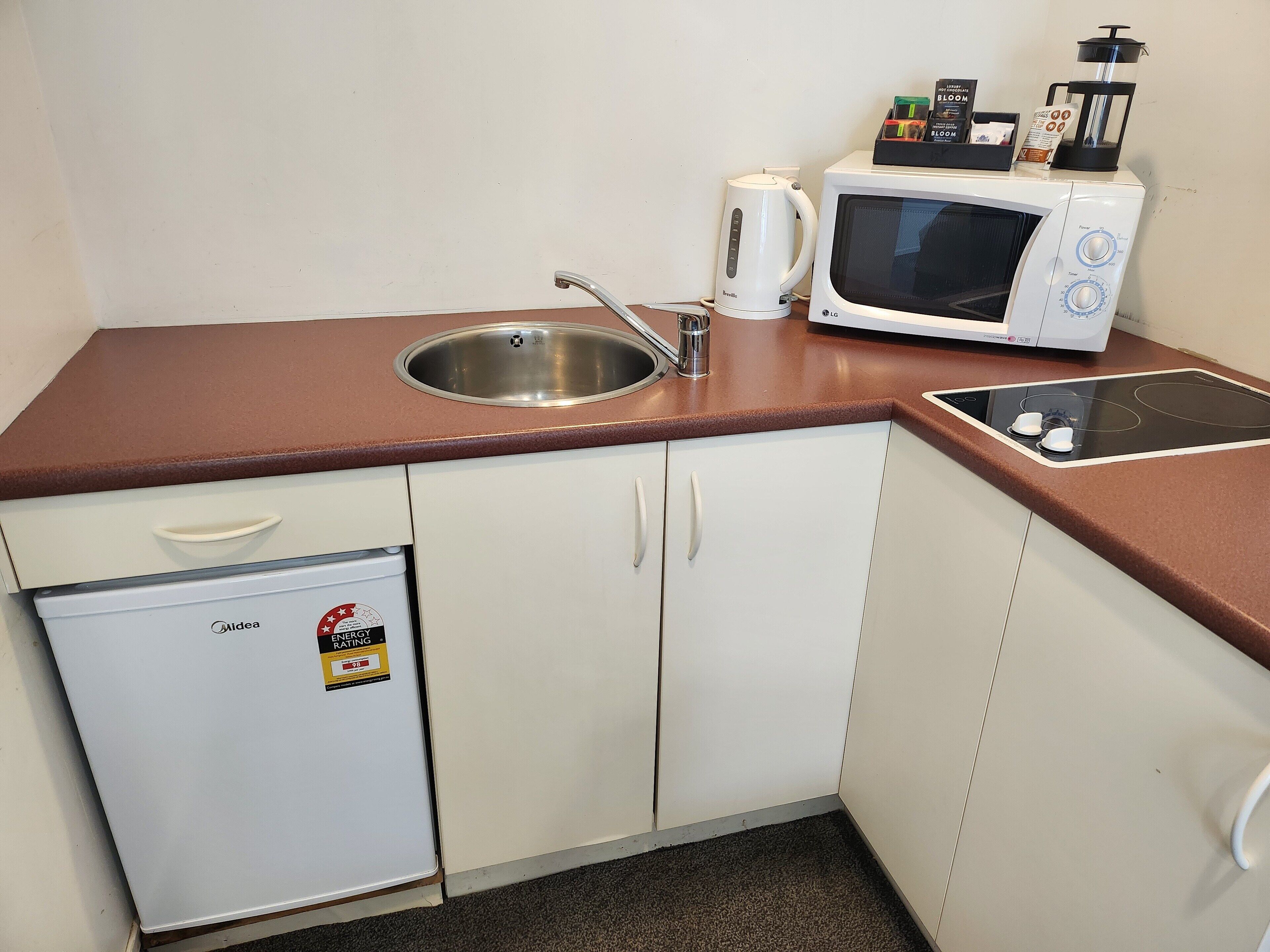 A compact kitchenette with a sink, a microwave, a coffee maker, and a small refrigerator.