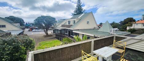 A residential area with houses, a tree, and a fenced patio with yellow metal chairs.
