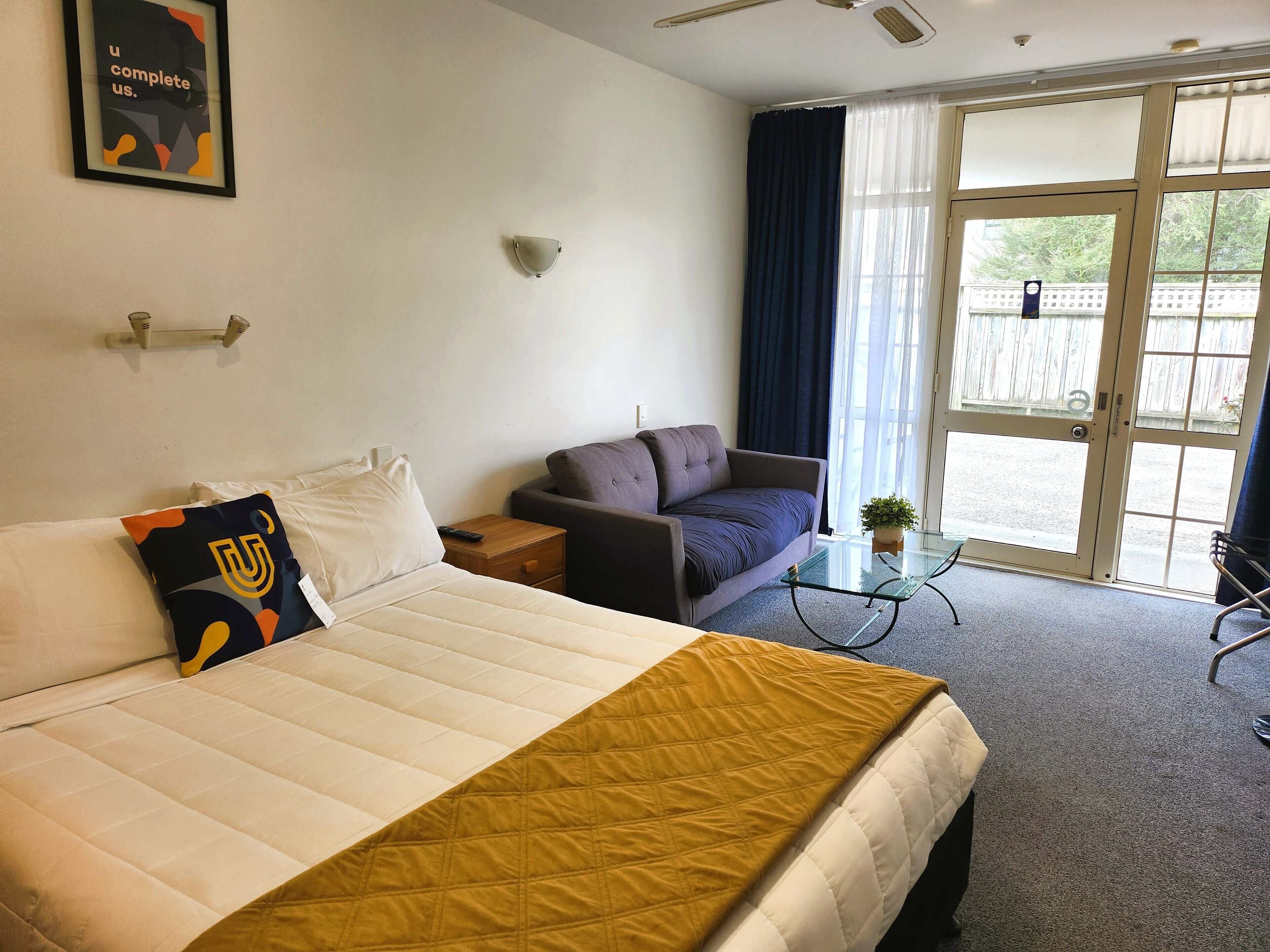 Una camera d'albergo con un letto, un divano, un tavolino e una finestra con tende.