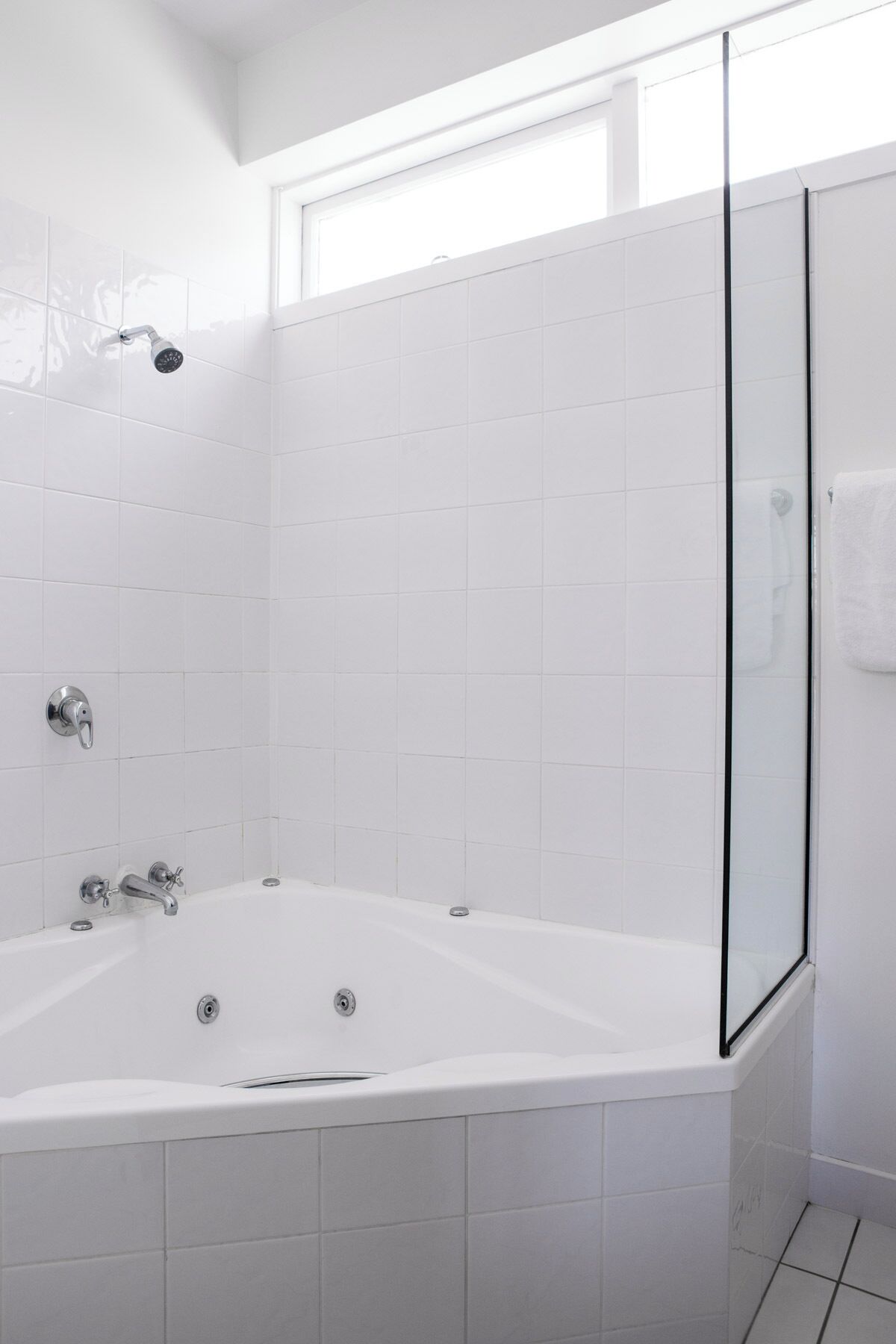 A modern bathroom with a freestanding bathtub, a glass shower enclosure, and white tiled walls.