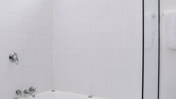 A modern bathroom with a freestanding bathtub, a glass shower enclosure, and white tiled walls.