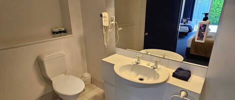 Un baño moderno con inodoro, lavamanos y espejo.