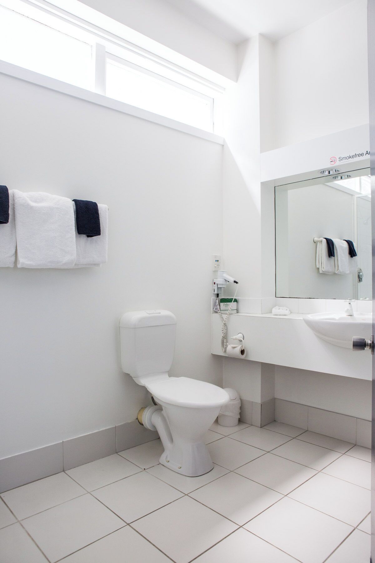 Ein modernes Badezimmer mit Toilette, Waschbecken und Handtuchhalter.