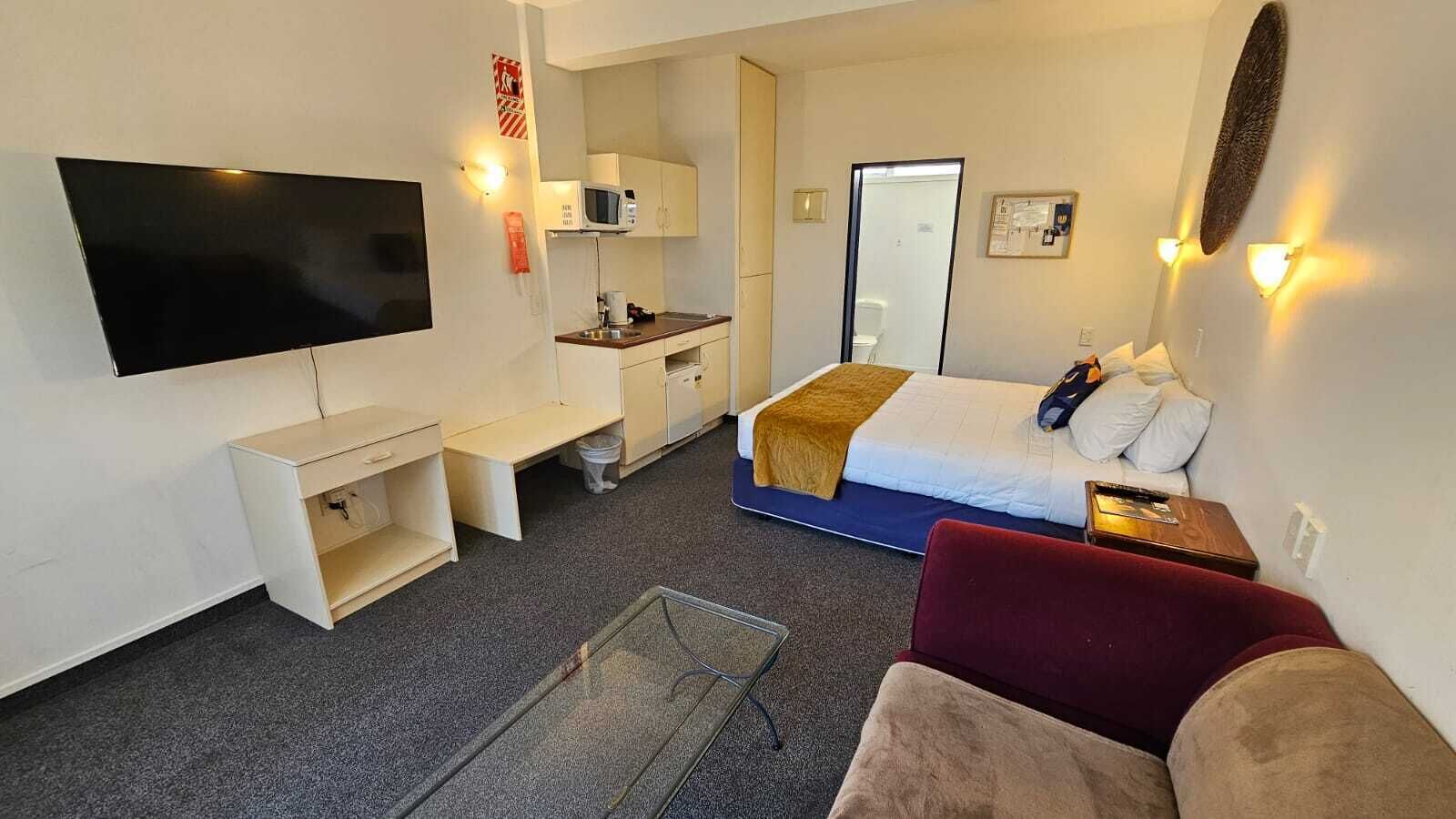 A hotel room with a bed, a TV, a desk, a chair, and a couch.
