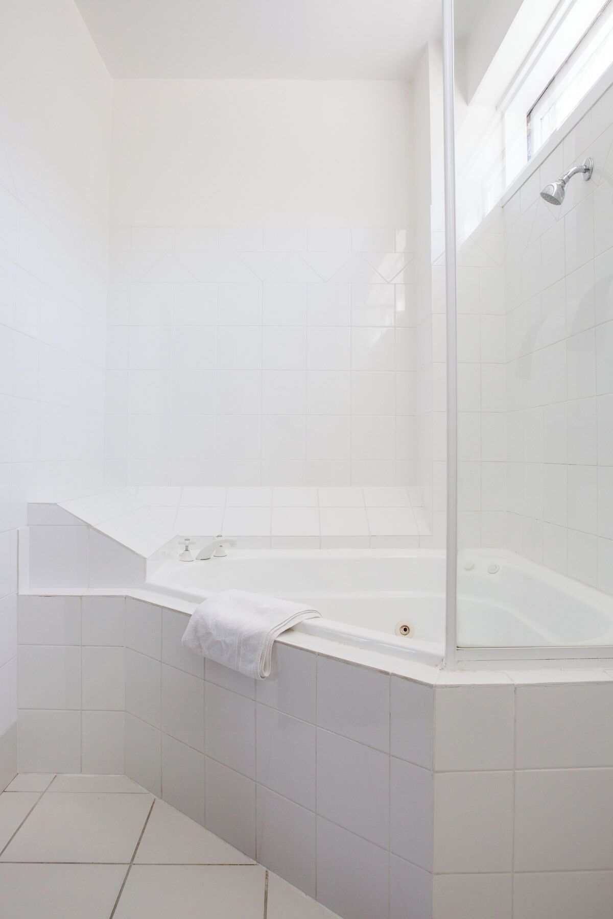 Un baño moderno con una bañera independiente, cabina de ducha con mampara de vidrio y paredes de azulejos blancos.