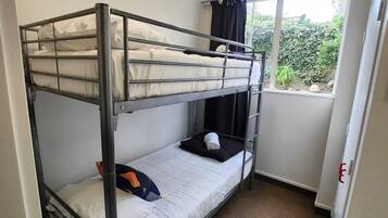 A bunk bed room with a window and a door.