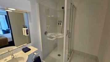 A modern bathroom with a glass-enclosed shower, a sink, and a mirror.