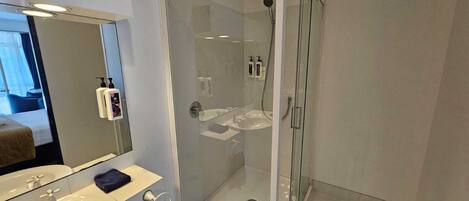 A modern bathroom with a glass-enclosed shower, a sink, and a mirror.