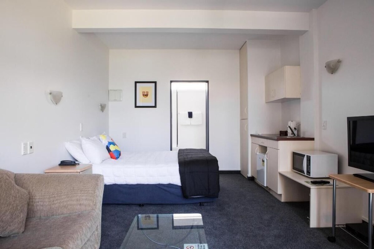 Ein Hotelzimmer mit einem Bett, einem Schreibtisch, einem Fernseher, einer Mikrowelle und einer Tür.