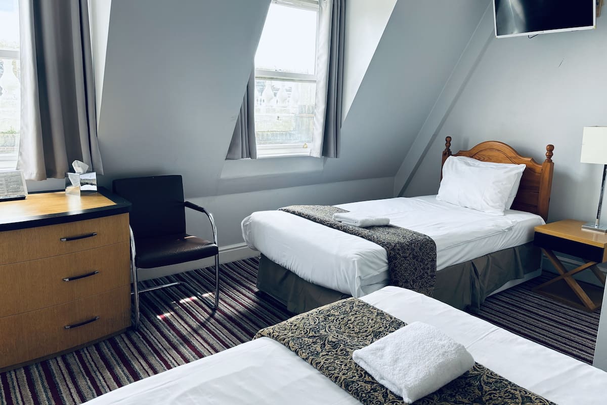 Una camera d'albergo con un letto, una scrivania, una sedia e una TV.
