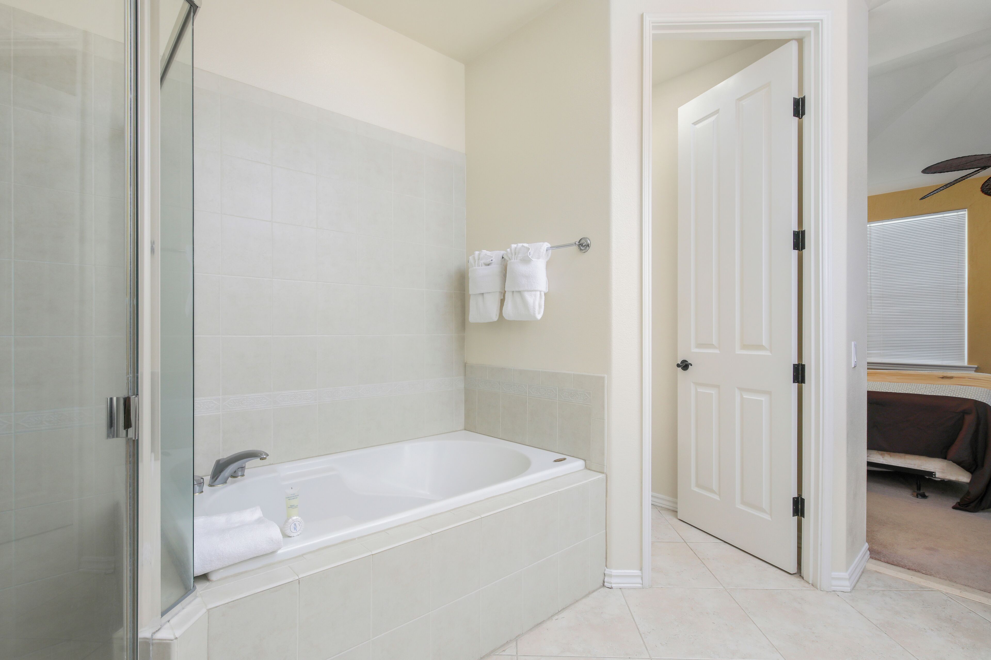 Un baño moderno con ducha envuelta en vidrio, bañera independiente y toallero con dos toallas.