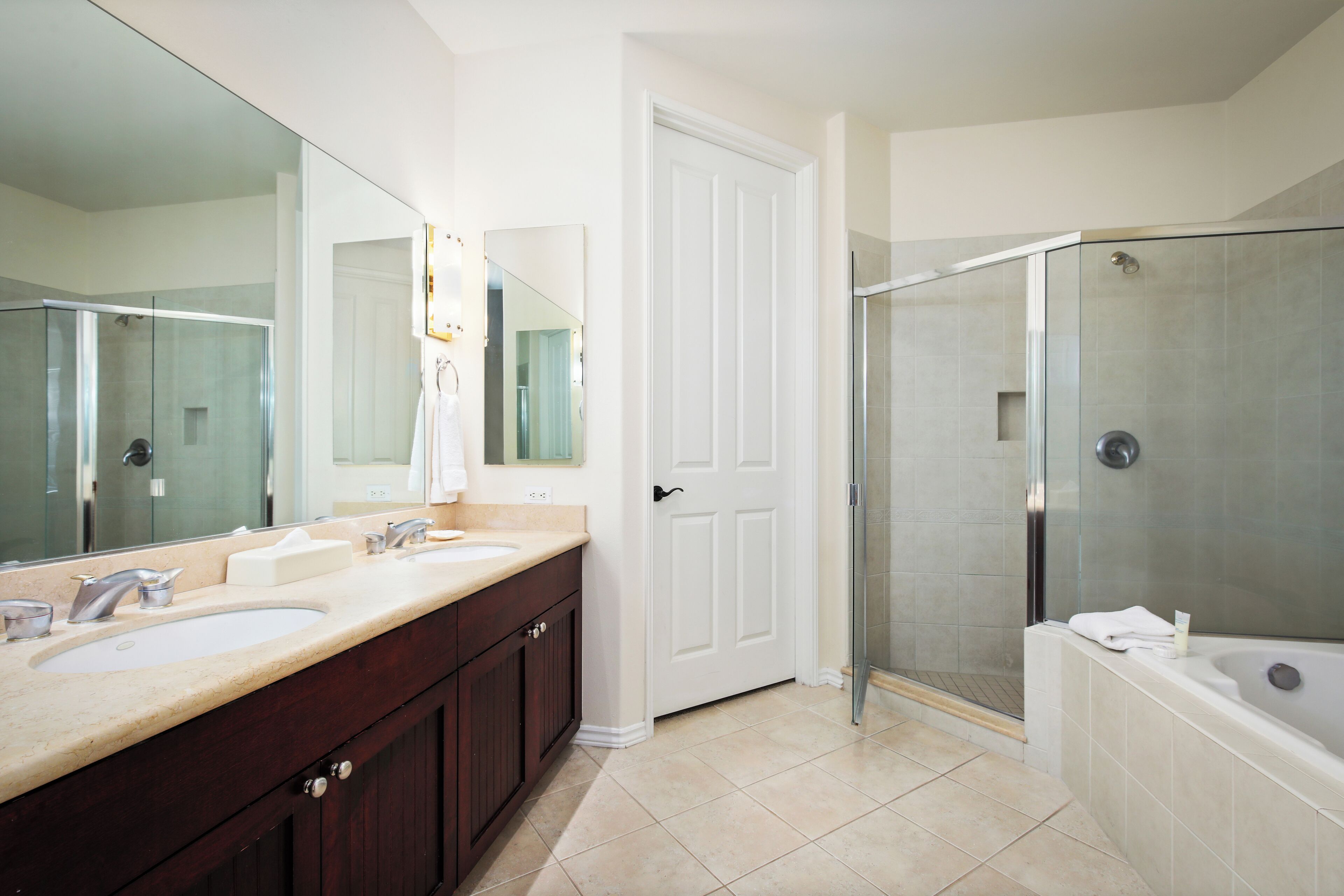 A bathroom with a double sink vanity, a large mirror, a shower enclosure, and a bathtub.