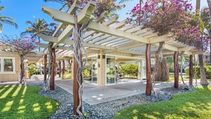 Un espacio al aire libre cubierto con una pérgola, árboles y un sendero.