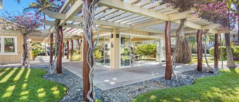 A covered outdoor area with a pergola, trees, and a pathway.