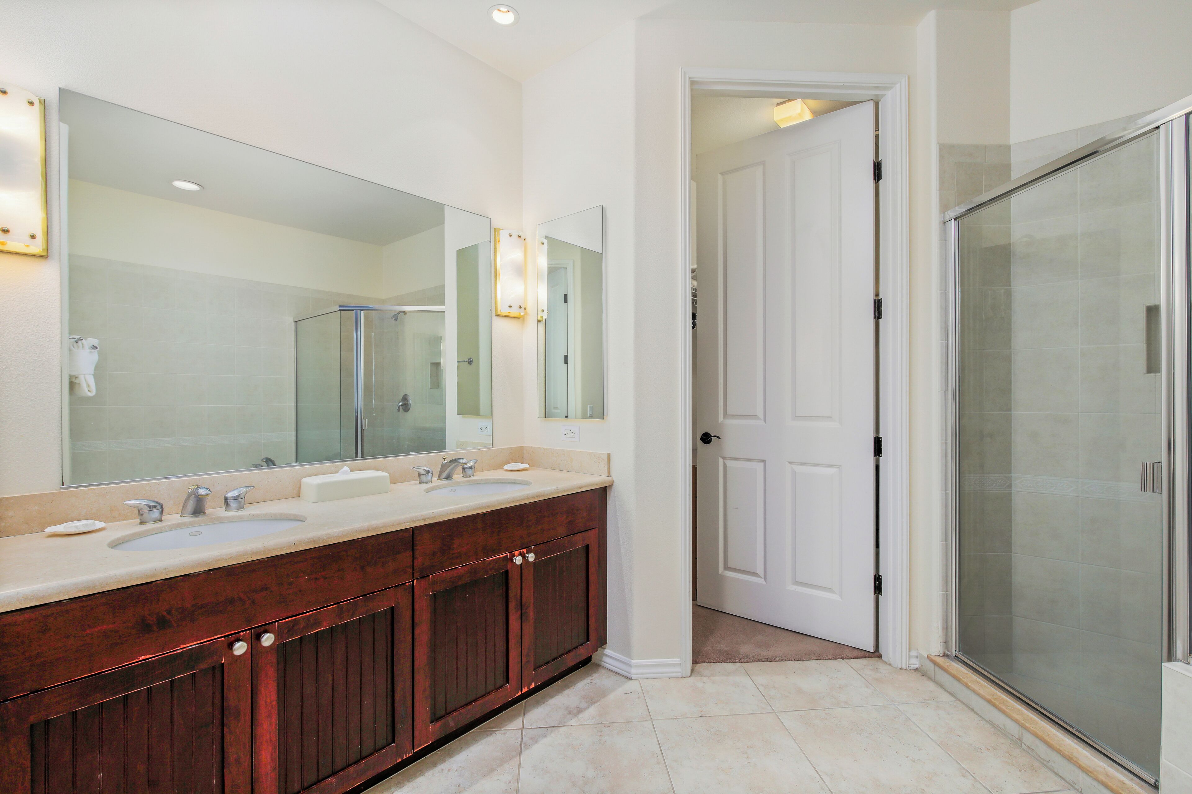 A bathroom with a double sink vanity, a large mirror, and a glass shower enclosure.