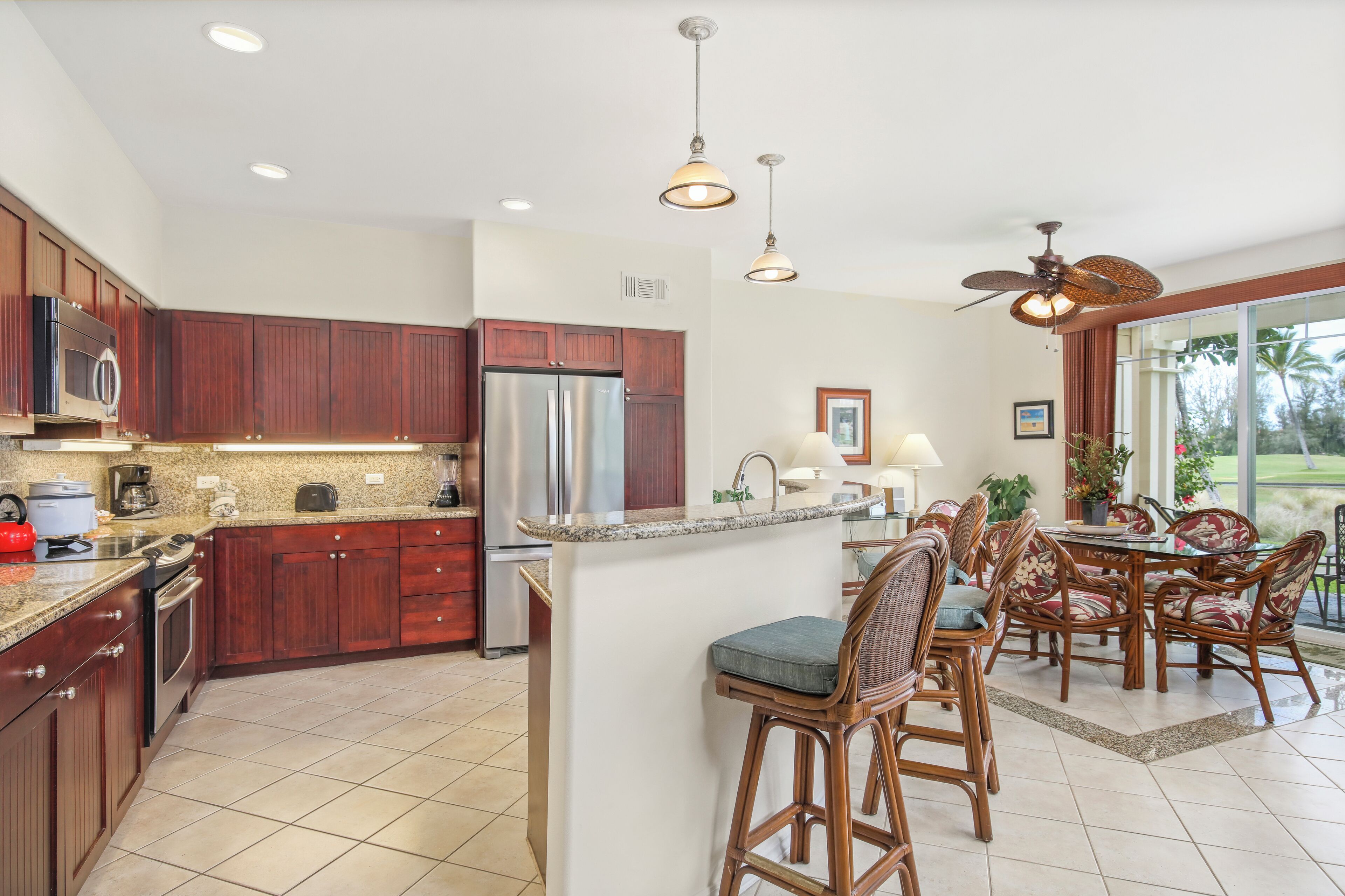 A spacious kitchen with wooden cabinets, stainless steel appliances, and a central island with bar stools.