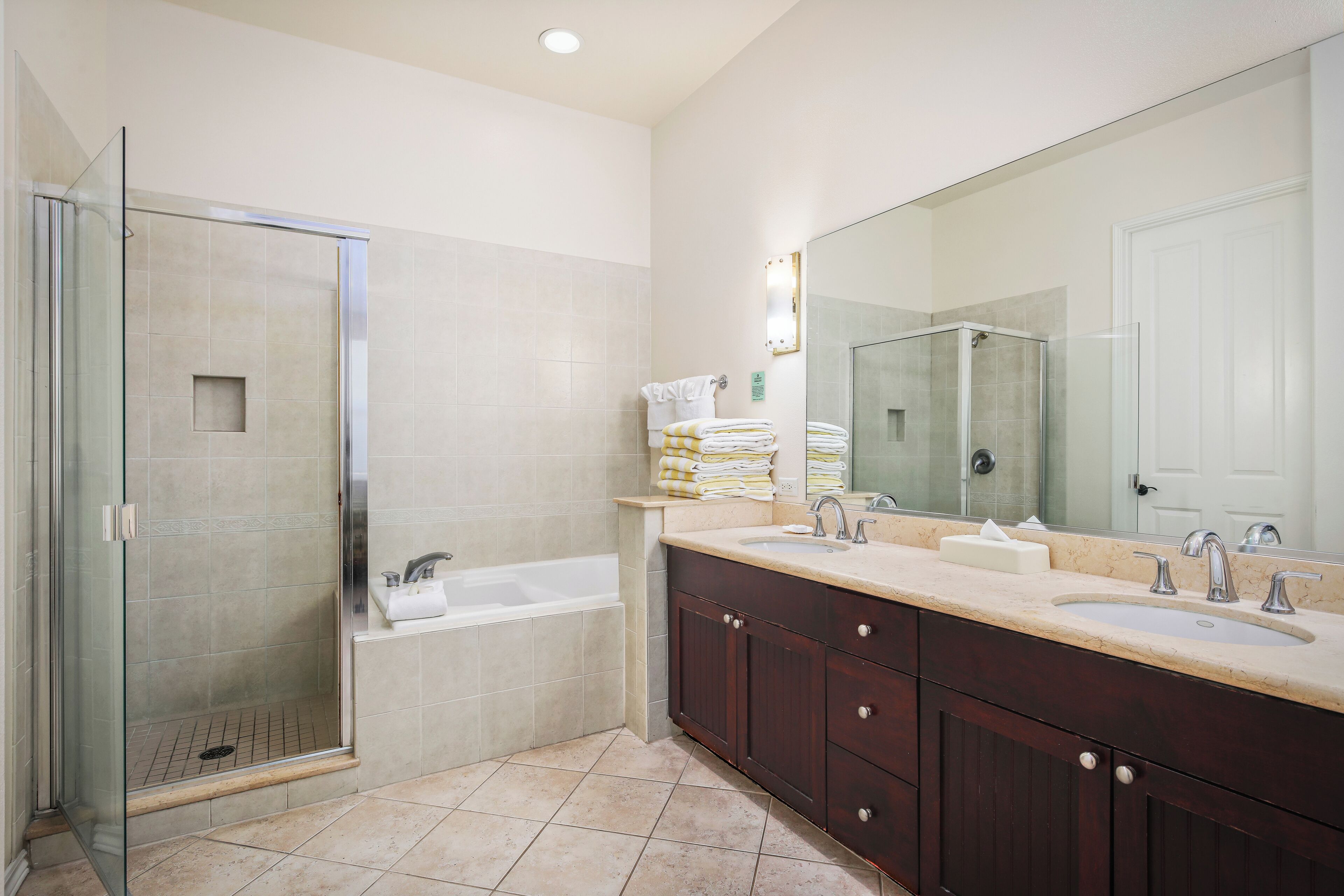 A modern bathroom with a glass-enclosed shower, a bathtub, and a vanity with dual sinks.