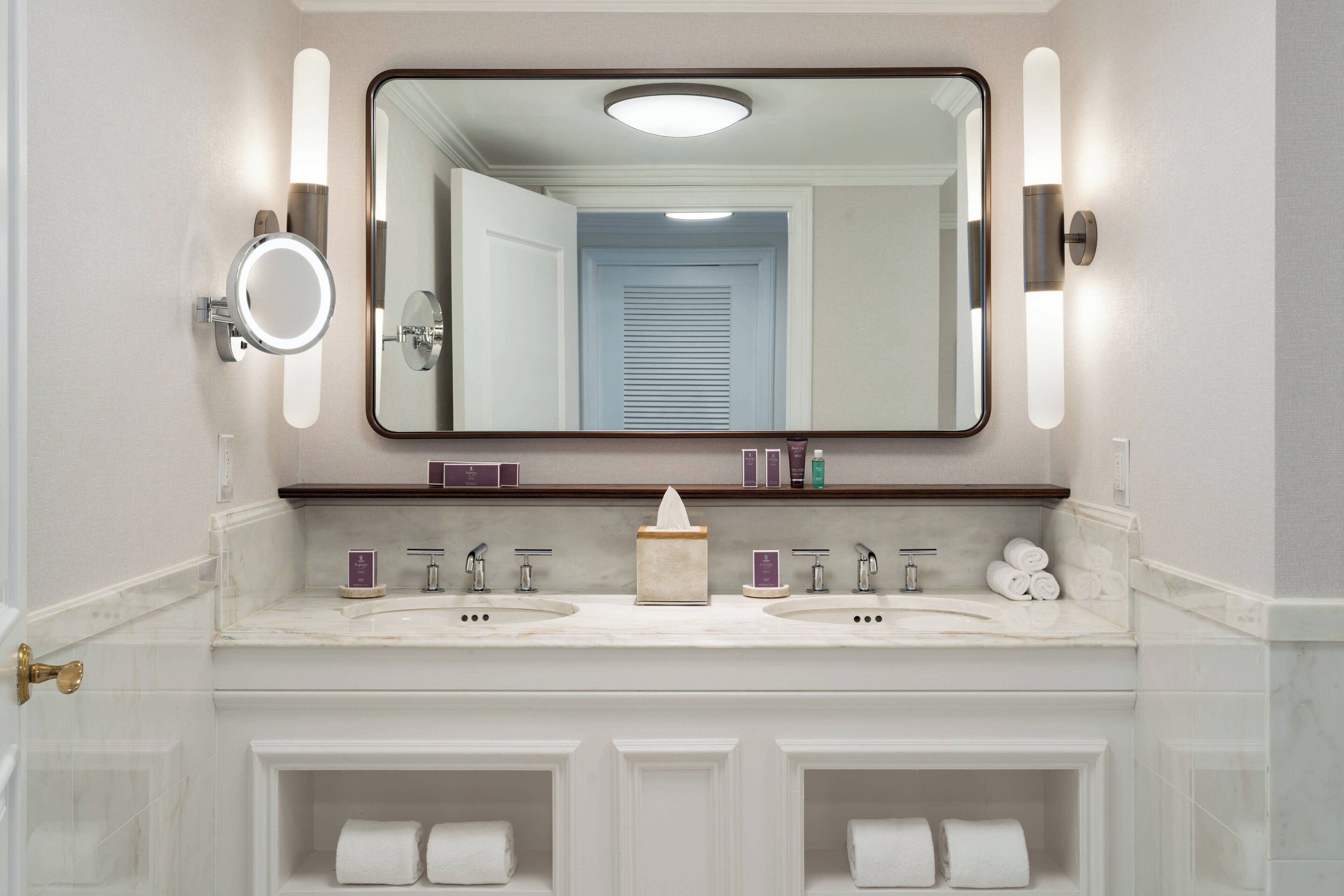 A bathroom with two sinks, a mirror, and a towel rack.