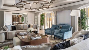 Un salon spacieux agrémenté d’un lustre moderne, d’un fauteuil bleu et d’un canapé beige.