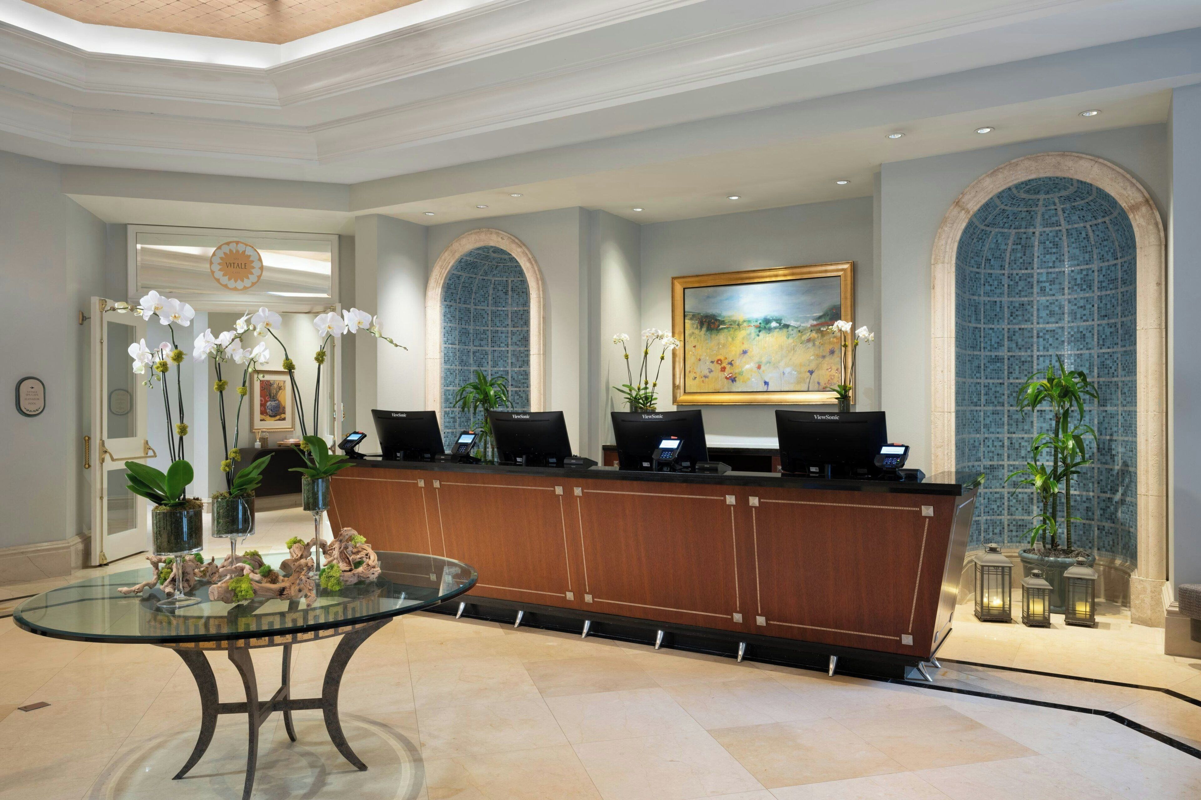 A reception area with a glass-top desk, reception counters, and a painting on the wall.