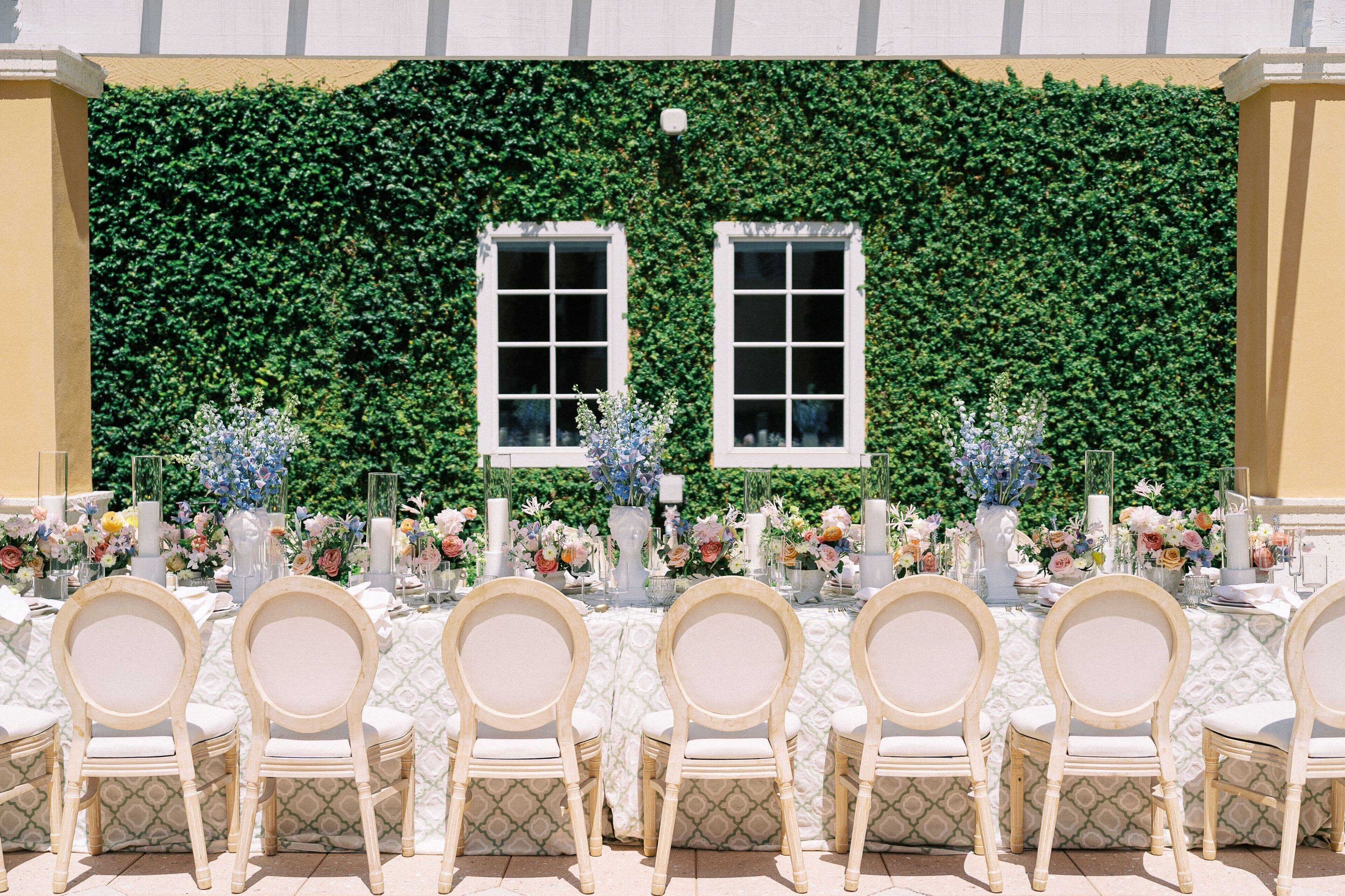 A table set for a formal event with white chairs and floral centerpieces.