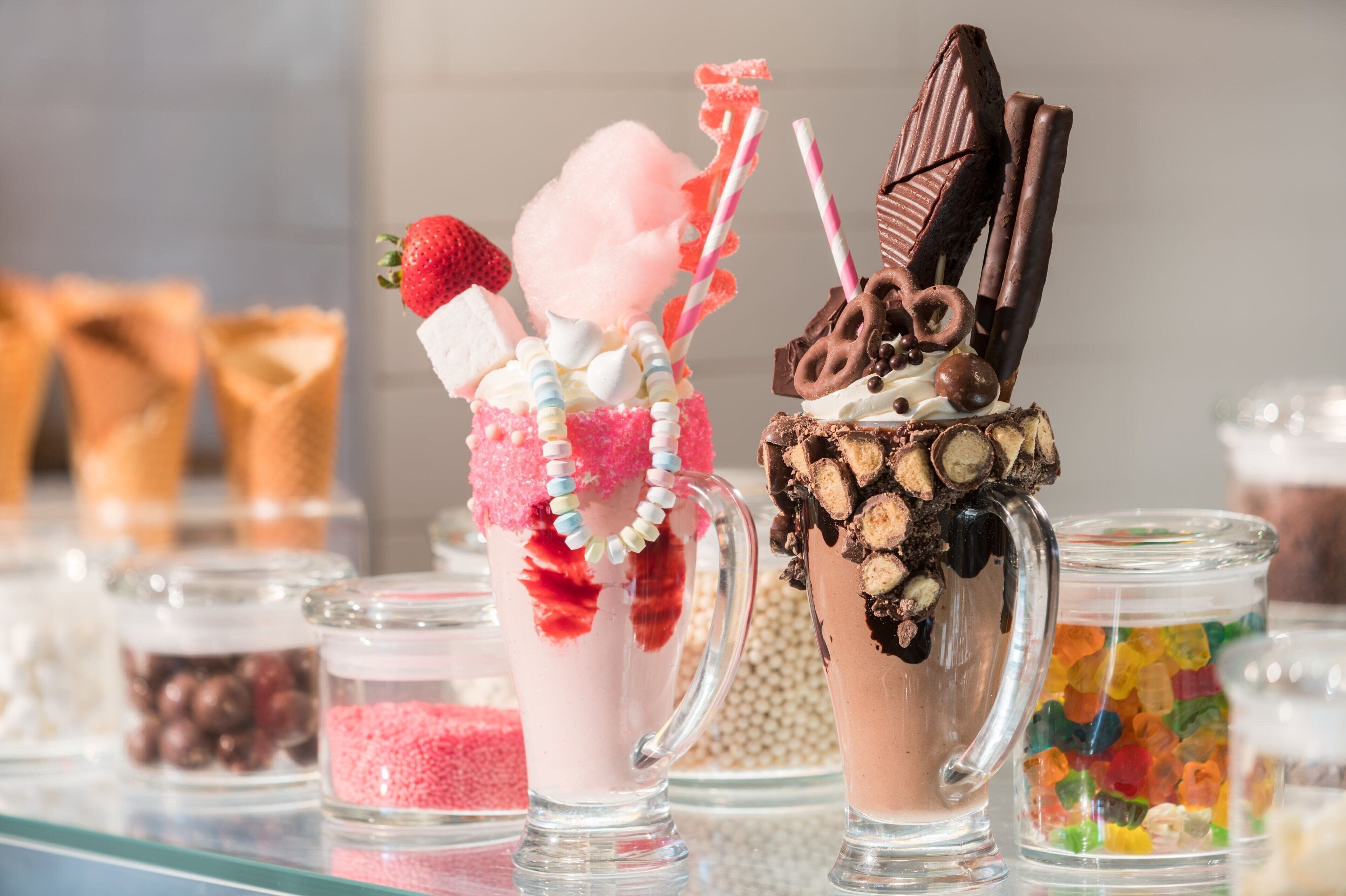 Two dessert drinks in clear glasses with various toppings and decorations.