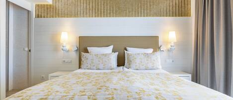 A hotel room with a large bed, two bedside lamps, a headboard, and a window with curtains.