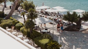 A beachside patio with outdoor seating and umbrellas, overlooking the sea. - Hotel Illa D'Or (Pollenca)