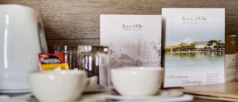 Een tafel met een koffiezetapparaat, kopjes en een menukaart voor ILLA D'OR Wellness & Spa Hotel.