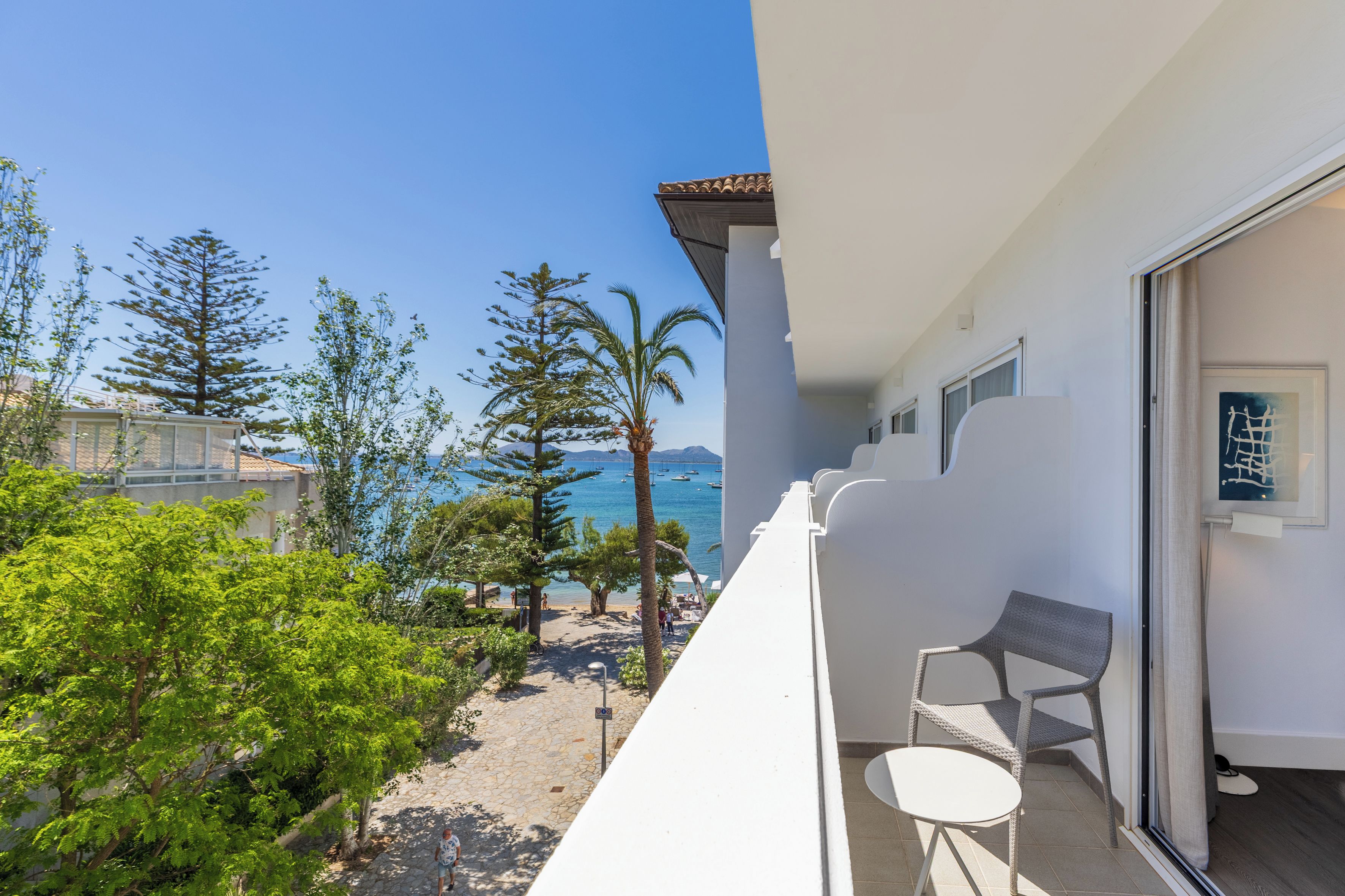 Un balcón con vista al mar, una silla y una puerta.
