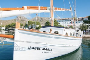 A white sailboat named 'ISABEL MARIA' docked at a marina with buildings and trees in the background.