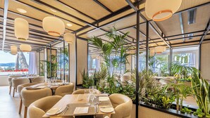 A restaurant with round tables, chairs, and hanging lights. - Hotel Illa D'Or (Pollenca)