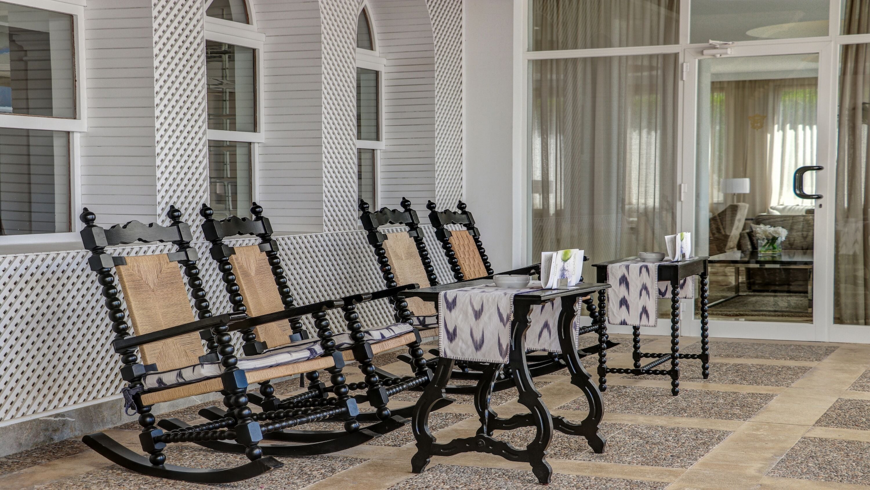 Una habitación con zona de estar que incluye sillones mecedores y una mesa con mantel estampado.