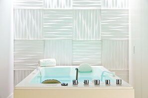 A modern bathroom with a bathtub, a towel, and a sink with multiple faucets.