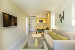 A modern living room with a sofa, a small round table, and a TV mounted on the wall.