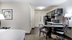 Een hotelkamer met een bed, bureau, stoelen en een kitchenette.