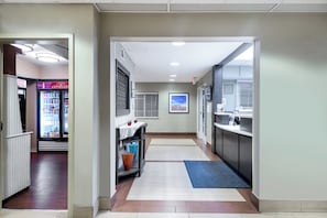 Un pasillo de hotel con una zona de kitchenette, un refrigerador y una cafetera.