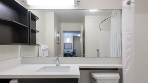 Een moderne badkamer met een witte wastafel, donkere kastjes, een toilet en een douchegordijn.