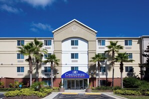 Een Canilever Suites hotel met een centrale ingang, meerdere verdiepingen en palmbomen.