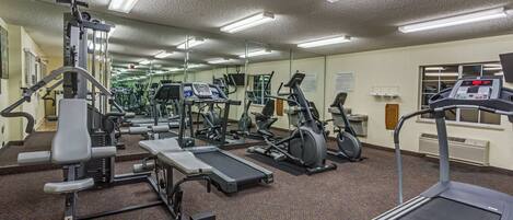 A gym with various exercise equipment, including treadmills, stationary bikes, and weight machines.