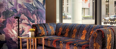 A modern living room with a sofa, a small round table, and a large abstract painting.