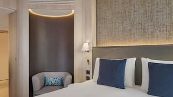 Hotellihuone, jossa on sänky, oleskelualue, seinään kiinnitetty valaisin ja kuvioitu seinä.