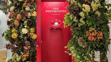 A red telephone booth with a floral arrangement on top and a sign that reads "The Westminster London".