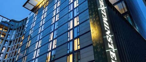 A modern hotel with a prominent 'RIU' sign, large windows, and a well-lit facade.