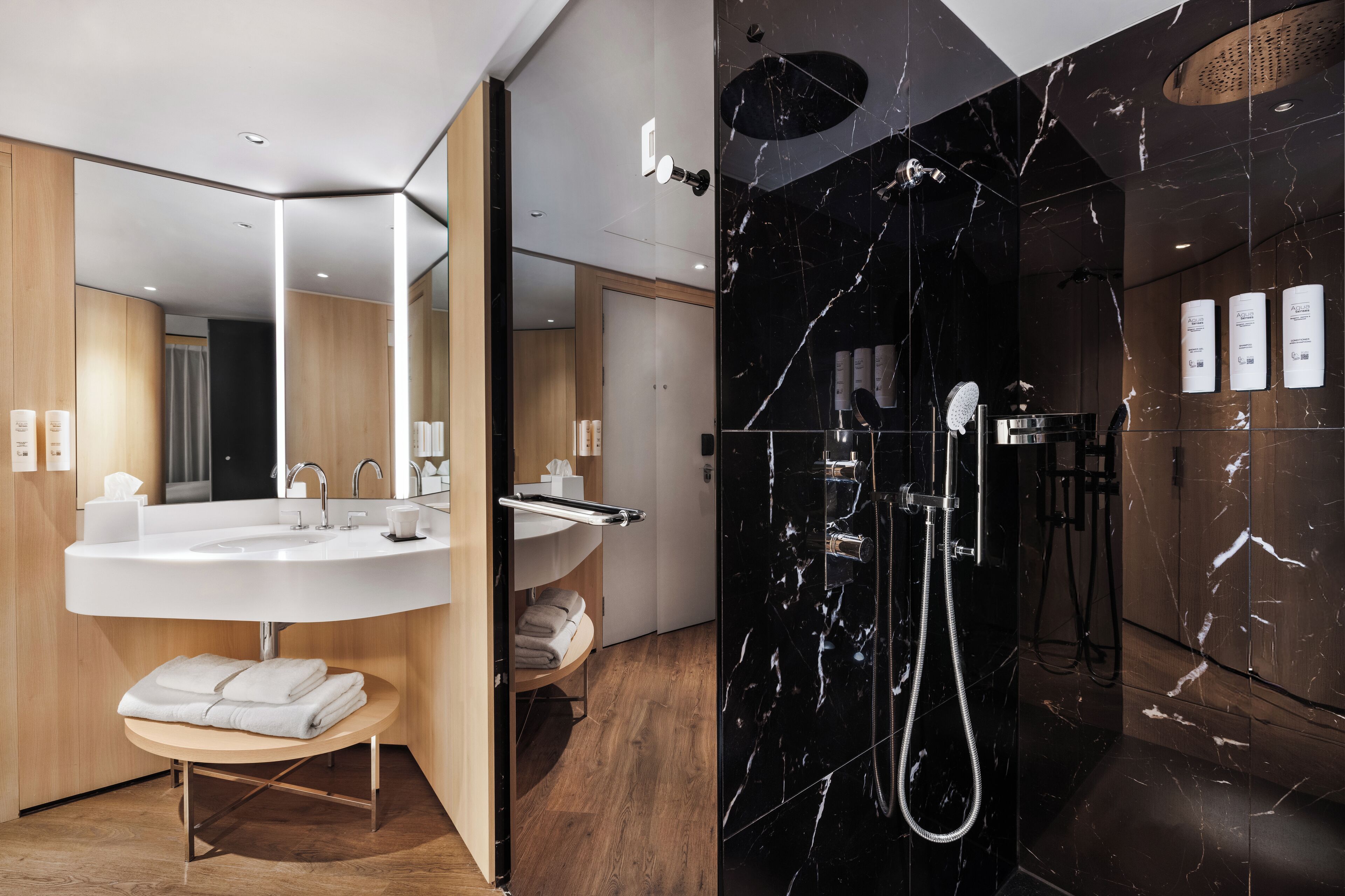 A modern bathroom with a large sink, mirror, and a separate shower area with marble walls.