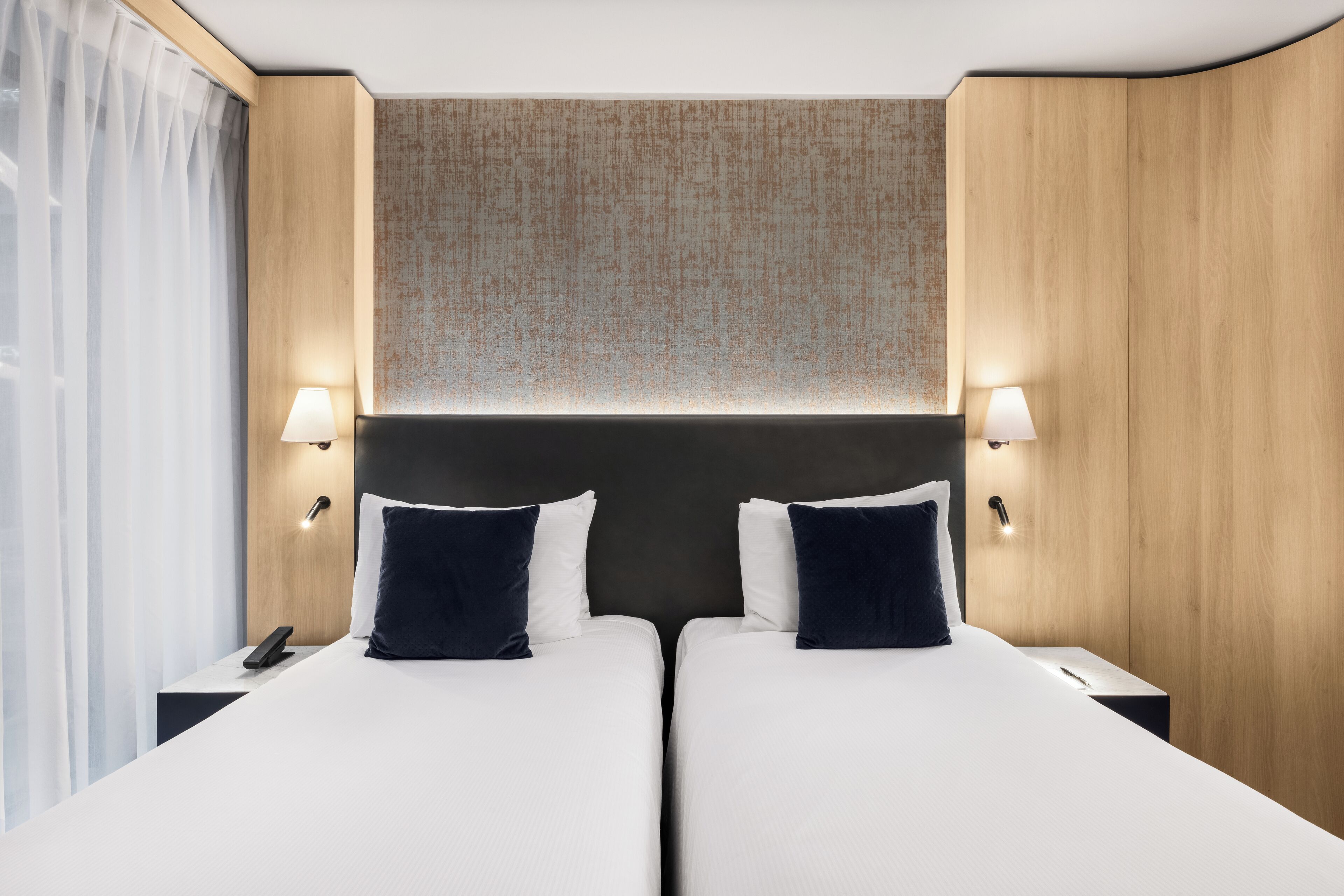 A hotel room with two beds, a wooden headboard, and bedside lamps.